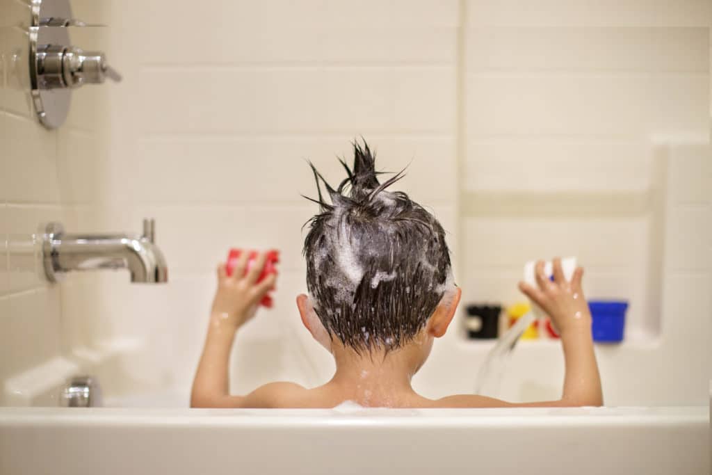 Kind mit Bechern in Badewanne